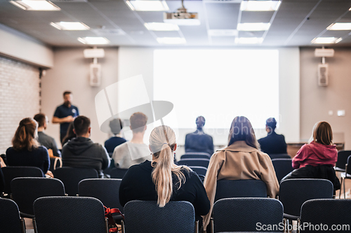 Image of Speaker giving a talk in conference hall at business event. Rear view of unrecognizable people in audience at the conference hall. Business and entrepreneurship concept.