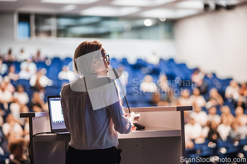 Image of Female speaker giving a talk on corporate business conference. Unrecognizable people in audience at conference hall. Business and Entrepreneurship event.