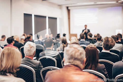Image of Speaker giving a talk in conference hall at business event. Rear view of unrecognizable people in audience at the conference hall. Business and entrepreneurship concept.