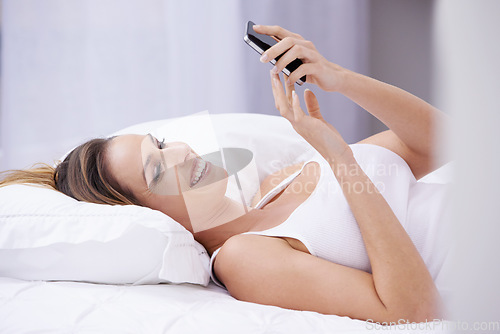 Image of Happy woman, relax on bed and phone for social media, reading online and communication or streaming. Young person in bedroom with mobile for chat, contact and internet connection for home on weekend