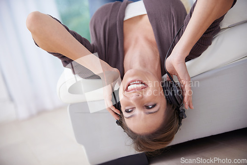 Image of Happy woman, upside down on couch and headphones for music, audio streaming and wellness with fun at home. Podcast, radio playlist and subscription online, relax in living room with technology