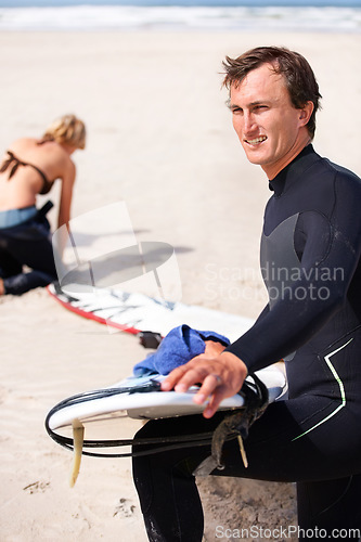 Image of Thinking, cleaning and man with surfboard on beach for sports, training or getting ready to workout. Summer, vision and wax with confident surfer on sand by ocean or sea for fitness and exercise