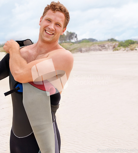 Image of Portrait, smile and man in wetsuit at beach for sports surfing, fitness or exercise on summer vacation. Travel, health and sand with happy young person getting ready for training or workout as surfer