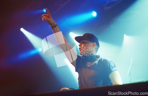 Image of Man, headphones and stage lighting for music performance or techno, festival or fans. Dj, hand and musician artist rock for audience at holiday event for dancing celebration or rave, venue or audio