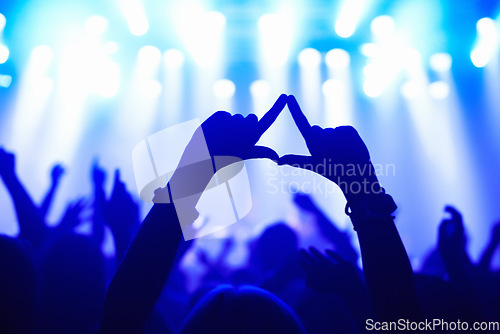 Image of Nightclub, concert and audience with hands or sign for music, party and rave festival with spotlight and dancing. Disco, rock event and performance with entertainment, crowd and rear view gesture