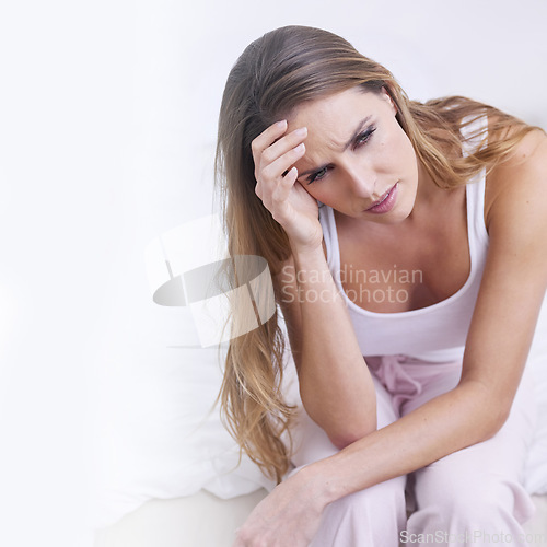 Image of Frustrated woman, headache and stress on bed in morning, wake up or mistake in depression at home. Upset young female person with migraine, anxiety or mental health sitting in bedroom on mockup space