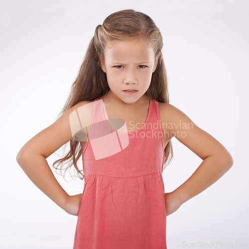 Image of Child, portrait and unhappy grumpy in studio or bad mood discipline or development, trouble or angry. Female person, hands and hips in frustration for girl kid as white background, attitude or mockup