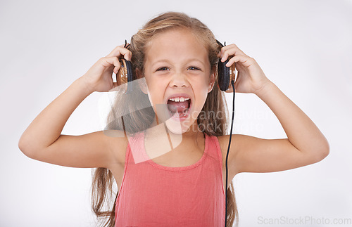 Image of Girl, headphones and screaming for noise in portrait, autism and sensory overstimulation in studio. Female person, kid and yelling for sound on white background, stress and frustration in childhood