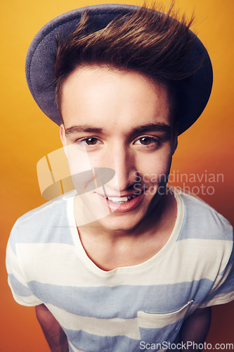 Image of Portrait, hat and man with fashion, smile and confident guy on an orange studio background. Face, person and model with accessory, student and aesthetic with casual outfit, trendy and stylish clothes