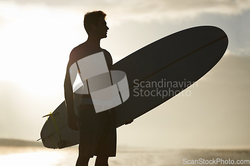Image of Surfing, sunset and silhouette of man at a beach with surfboard for freedom, travel or sports outdoor. Ocean, training and surfer shadow at sea for swimming, wellness or adventure, workout or holiday