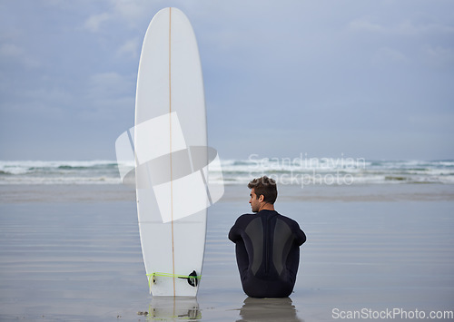 Image of Beach, fitness and man thinking with a surfboard for wellness, sports and training while sitting in nature. Water, exercise and back of male surfer at the ocean with peace, calm and sea hobby in Bali