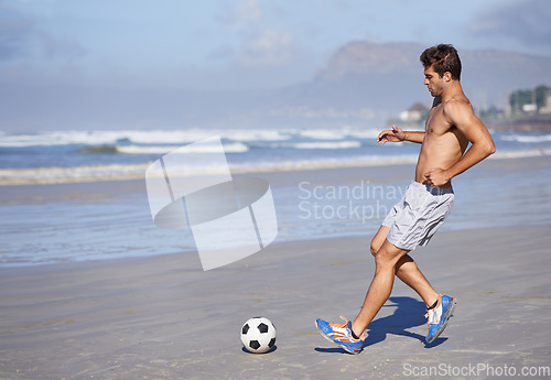 Image of Man, beach and playing soccer for game, sports or exercise in outdoor hobby, training or practice. Young male person or football player with ball on ocean coast for match or cardio workout by seaside