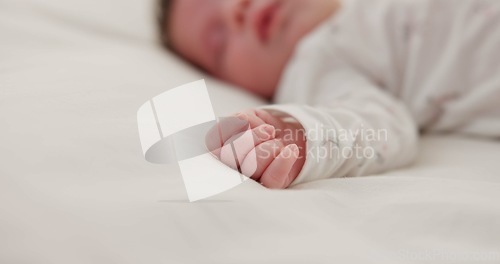 Image of Hand, newborn and sleeping on bed in nursery with relaxing, resting and nap on blanket in morning. Baby, peaceful and dreaming in bedroom of home for child development, growth and nurture or relax