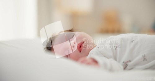 Image of Tired, sleeping and newborn baby on a bed at a home in the bedroom for resting and dreaming. Cute, sweet and little infant, child or kid taking a nap in the morning in the nursery at family house.