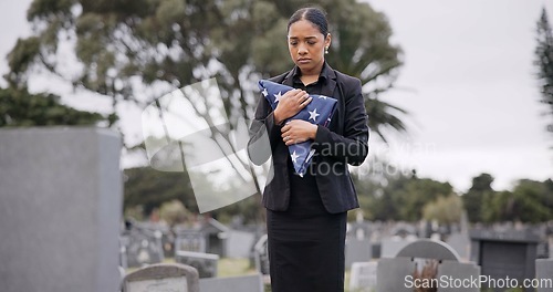 Image of Funeral, death and a sad woman with an american flag at a cemetery in mourning at a memorial service. Sad, usa and an army wife as a widow in a graveyard alone feeling the pain of loss or grief