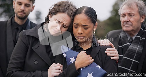 Image of Funeral, death and support for a woman with a flag at a cemetery in mourning at a memorial service. Sad, usa and an army wife as a widow in a graveyard feeling the pain of loss or grief with a friend