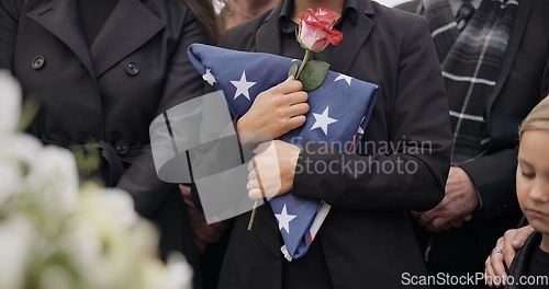 Image of Funeral, graveyard and woman with American flag for veteran for respect, ceremony and memorial service. Family, depression and sad people with flower in cemetery for military, army and soldier hero