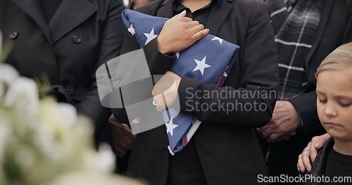 Image of Funeral, cemetery and woman with American flag for veteran for respect, ceremony and memorial service. Family, depression and sad people by coffin in graveyard for military, army and soldier mourning