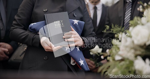 Image of Hands, american flag and bible with a person at a funeral, grieving a loss at a graveyard. War, cemetery and death with an army wife at a memorial service to say goodbye to a fallen soldier closeup