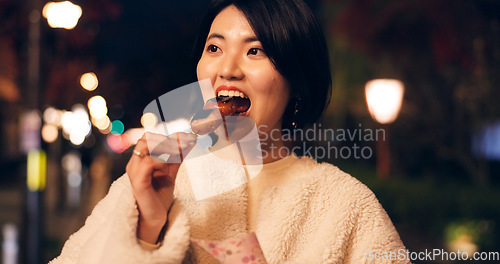 Image of Woman, street food and eating Japanese snack for travel experience, hungry or local trip. Female person, sidewalk and night or bite grilled mochi on road for vacation culture, adventure or tradition
