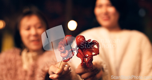 Image of Women, Japan and travel street food at night for octopus delicacy, culture or traditional. Female people, snack and stick for tourism eating experience or cuisine in town for taste, dinner or holiday