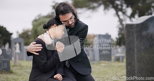 Image of Sad couple, graveyard and hug in loss, grief or mourning together at funeral, tombstone or cemetery. Man holding woman in comfort, empathy or goodbye at memorial or burial service for death on grass