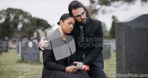 Image of Sad couple, rose and graveyard in loss, grief or mourning at funeral, tombstone or cemetery. Man and woman hug with flower in depression, death or goodbye at memorial or burial service for loved one