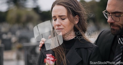 Image of Support, death or couple in cemetery for funeral. spiritual service or burial to repsect the Christian religion. Rose, depressed or sad people hug for comfort in graveyard for grief, loss or mourning