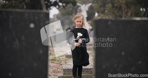 Image of Sad, death or kid in cemetery for funeral. spiritual service or grave visit for respect in Christian religion. Mourning, tomb or depressed girl child outside in graveyard for grief, loss or farewell