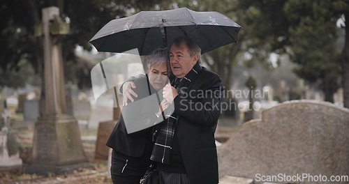 Image of Support, death or old couple in cemetery for funeral, service or burial for repsect in Christian religion. Umbrella, depressed or sad senior people hug for comfort in graveyard crying in mourning