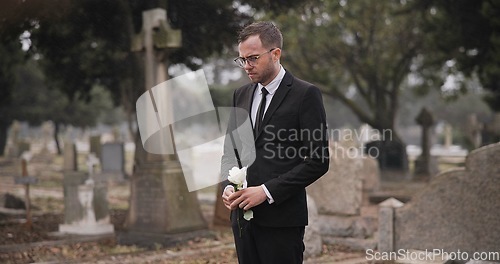 Image of Funeral, cemetery and man with flower by tombstone for remembrance, burial ceremony and memorial service. Depression, sad and person with rose by gravestone for mourning, grief and loss in graveyard