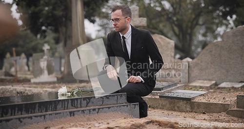 Image of Funeral, cemetery and man with flower at tombstone for remembrance, burial ceremony and memorial service. Depression, death and person with rose for mourning, grief and loss in graveyard for respect