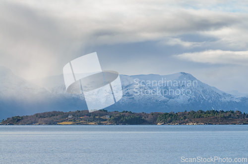 Image of Snow-Capped Mountain View Across the Calm sea Under a Cloudy Sky