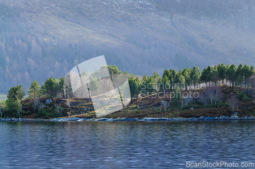 Image of Serene sea view with forested hillside and misty mountains at da