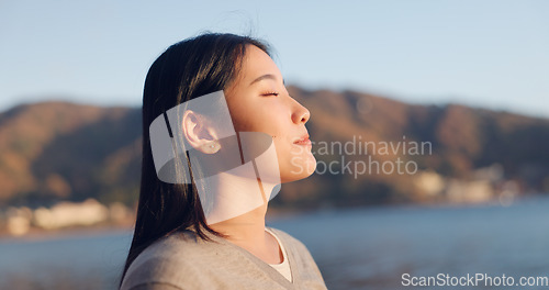 Image of Japanese woman, breathing and peace outdoor, lake or ocean with travel, holiday and mindfulness in nature. Wellness, adventure and care free at beach in Japan, calm with freedom and positivity