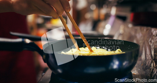 Image of Cooking, restaurant and person with noodles in pan on gas stove at market for meal preparation, eating and cuisine. Culinary, flame and closeup of chopsticks to prepare lunch, dinner and supper