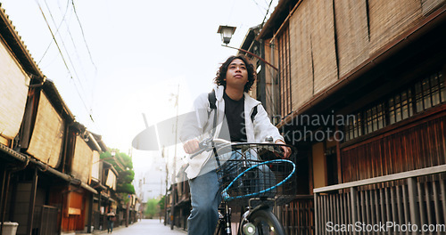 Image of Bike, travel and man riding by building for exercise or transportation to college academy. Fitness, backpack and young male student driving a bicycle to university for carbon footprint by houses.