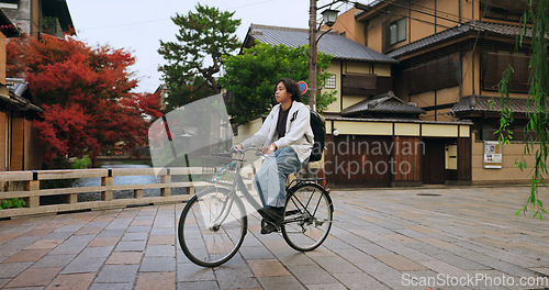 Image of Cycling, travel and man riding by buildings for exercise or transportation to college academy. Fitness, backpack and young male student driving a bicycle to university for carbon footprint by houses.