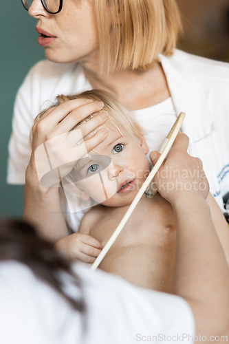 Image of Small child being checked for heart murmur by heart ultrasound exam by cardiologist as part of regular medical checkout at pediatrician.