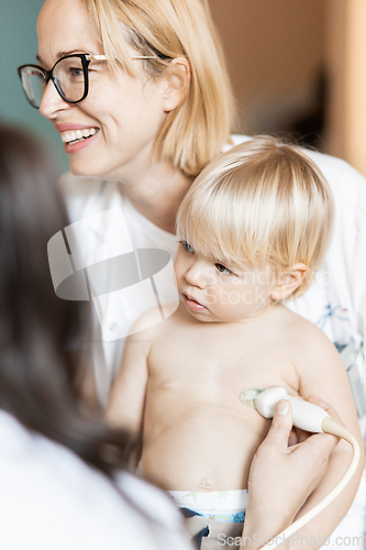 Image of Small child being checked for heart murmur by heart ultrasound exam by cardiologist as part of regular medical checkout at pediatrician.