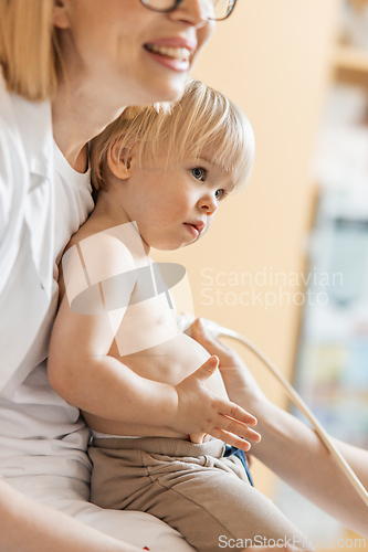 Image of Small child being checked for heart murmur by heart ultrasound exam by cardiologist as part of regular medical checkout at pediatrician.