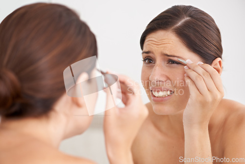 Image of Eyebrow, plucking and woman with pain for beauty, self care and mirror in bathroom. Makeup, routine and girl with hair removal, tools and facial grooming or treatment for skincare and cosmetics