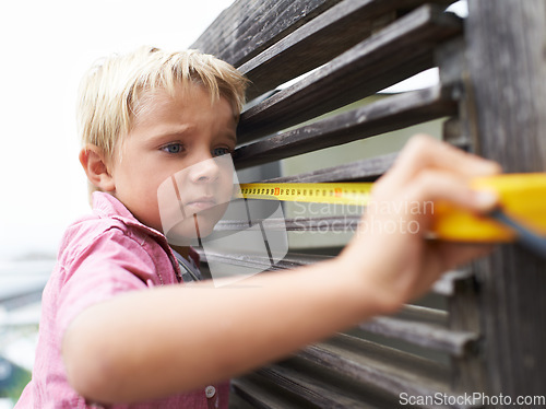 Image of Focus, measuring tape and young child doing maintenance on wood gate for fun or learning. Serious, equipment and little boy kid working on repairs with tool for home improvement outdoor at house.