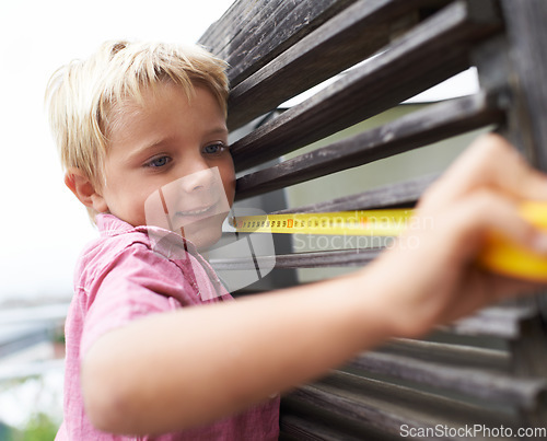 Image of Smile, measuring tape and boy kid doing maintenance on wood gate for fun or learning. Happy, equipment and young child working on handyman repairs with tool for home improvement outdoor at house.