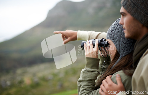 Image of Couple with binoculars, nature and mountains for travel journey, adventure and hiking or explore together. Man and woman trekking, pointing with outdoor search, vision or birdwatching lens in tourism