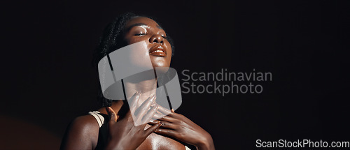 Image of Face, hands and skincare with a natural black woman on a dark background in studio for feminine wellness. Arms, beauty and spa with a confident young model touching her body or skin in satisfaction