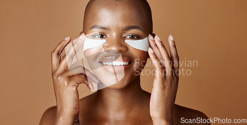 Image of Face, beauty or happy black woman with eye patch for skincare or wellness isolated on brown background. Studio, smile or model with facial collagen pads, dermatology product or anti aging cosmetics