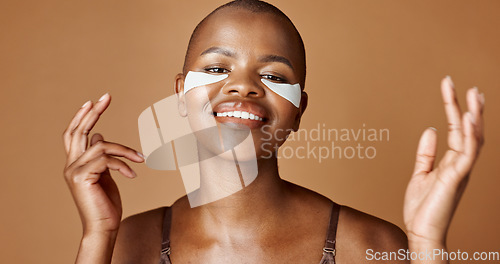 Image of Face, beauty or happy black woman with eye patch for skincare or wellness isolated on brown background. Studio, smile or model with facial collagen pads, dermatology product or anti aging cosmetics