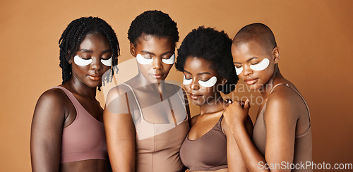 Image of Happy black woman, eye patches and skincare for beauty, epilation or anti aging against a brown studio background. Group portrait of African female people or model in dermatology, health and wellness