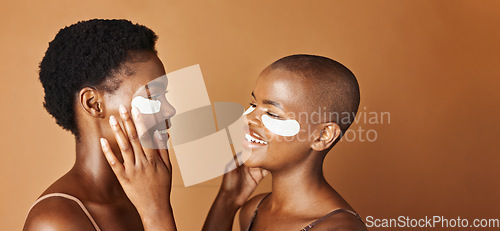 Image of Beauty, eye pads and face of black women in studio with glowing, natural and facial routine. Smile, skincare and portrait of African female friends with cosmetic treatment by brown background.